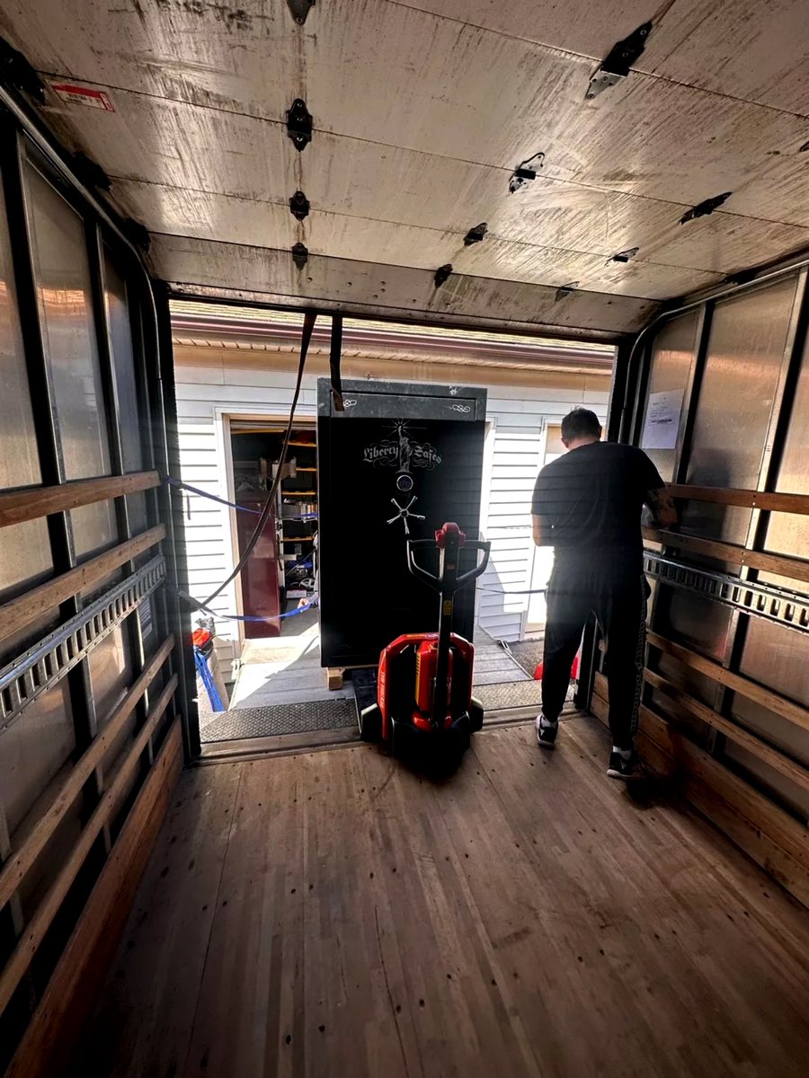 Crew moving a heavy gun safe with a pallet jack