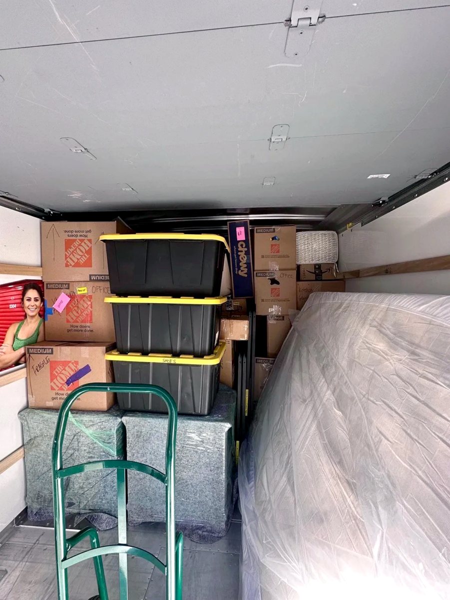 Moving truck packed with labeled boxes, bins, and a wrapped mattress